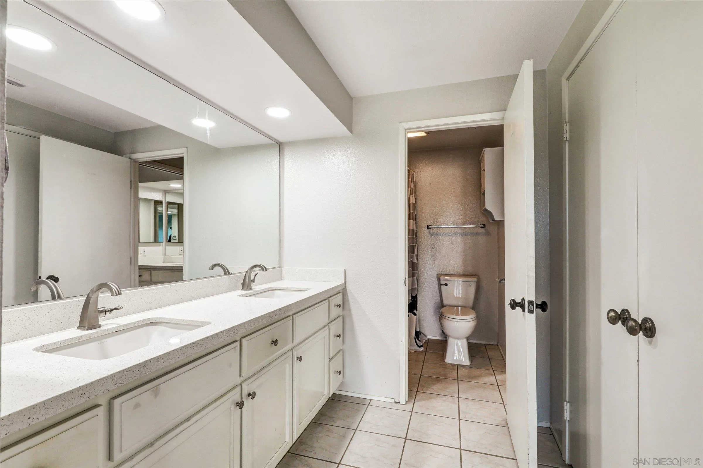 9488 Hiker Hill Road San Diego, CA 92129 - Photo 19 of 27 a spacious bathroom with a granite countertop sink and a mirror