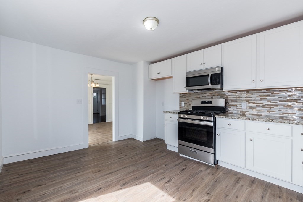 9 Camp Street Wareham, MA 02558 - Photo 12 of 30 a kitchen with granite countertop a stove top oven a sink dishwasher and a refrigerator with wooden floor