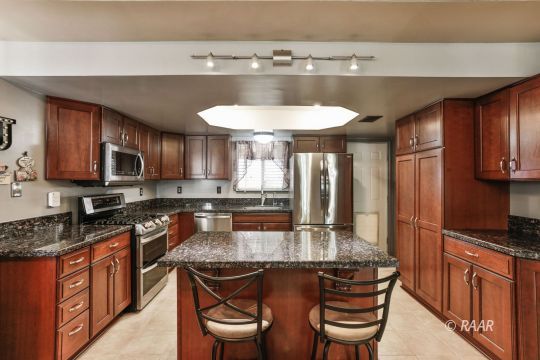 424 Mavis Court Ridgecrest, CA 93555 - Photo 9 of 32 a kitchen with stainless steel appliances granite countertop a sink a stove a kitchen island and chairs