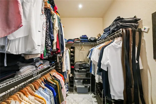 a view of walk in closet with clothes and shoes