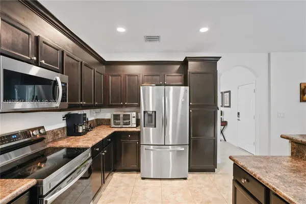 a kitchen with stainless steel appliances granite countertop a refrigerator a stove and a microwave