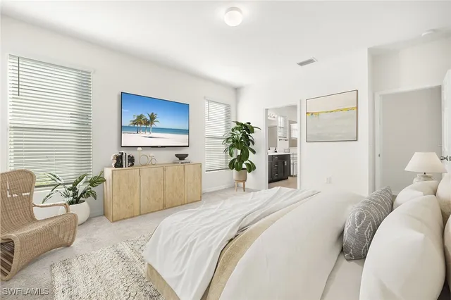 a bedroom with a large bed a couch and potted plant