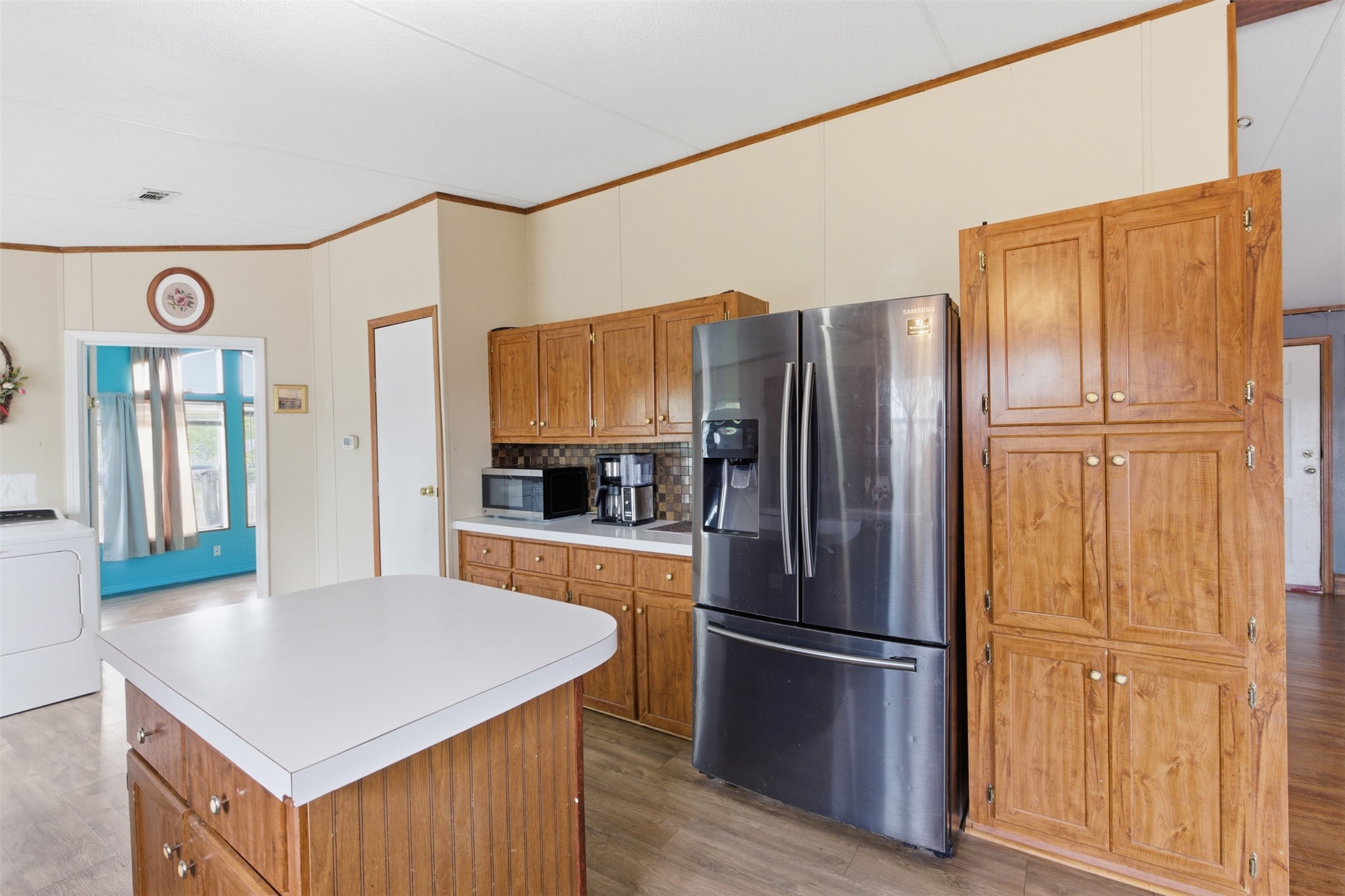 1150 Walter Hoffman Road Cedar Creek, TX 78612 - Photo 12 of 25 Kitchen featuring stainless steel appliances, light wood-type flooring, washer / dryer, ornamental molding, and wood finish cabinets