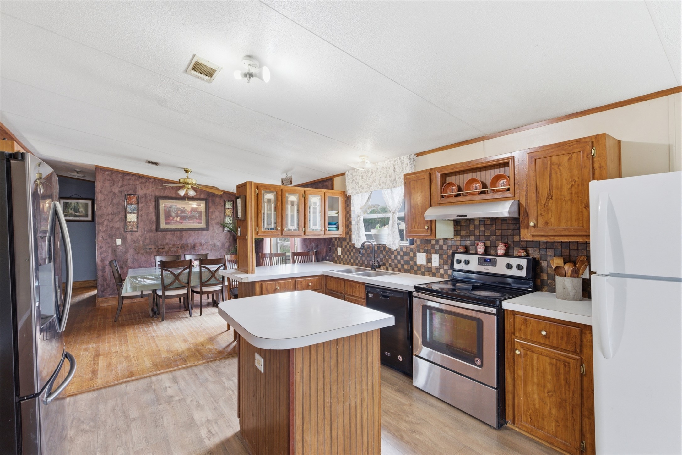 1150 Walter Hoffman Road Cedar Creek, TX 78612 - Photo 10 of 25 Kitchen featuring wood finish cabinets, stainless steel appliances, light countertops, ornamental molding, and wallpapered walls