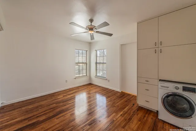 a view of empty room with wooden floor and fan