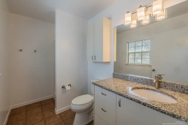 a bathroom with a granite countertop sink toilet and mirror