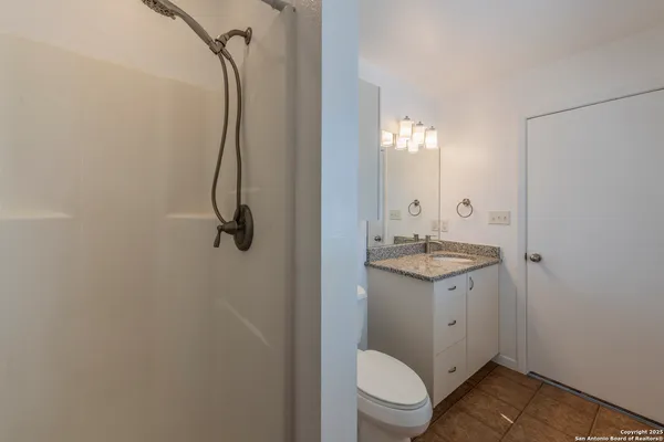 a bathroom with a granite countertop sink toilet and shower
