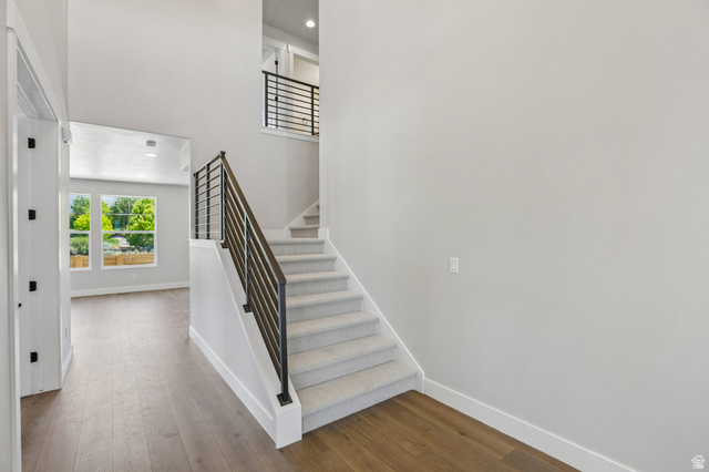 11781 South Halls Crk Road Draper, UT 84020 - Photo 4 of 33 Entryway featuring wood-finish flooring, a carpeted staircase with contemporary metal railings, and a two-story ceiling