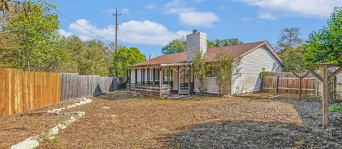 a view of a backyard with large trees and wooden fence