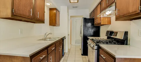 a kitchen with stainless steel appliances granite countertop a refrigerator a stove and a sink