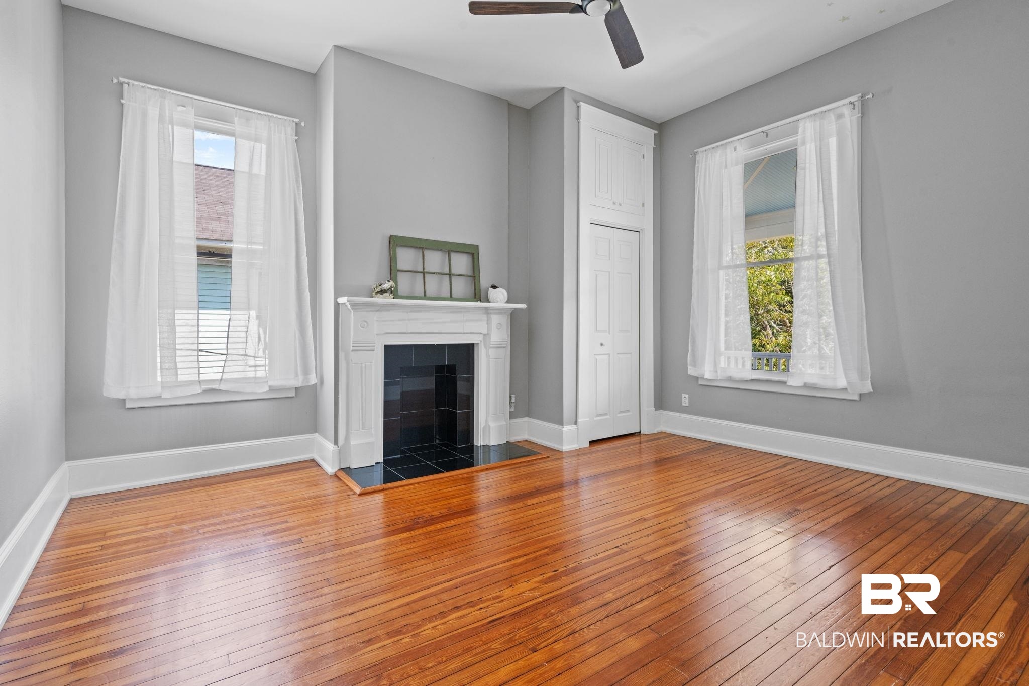 10 South Monterey Street Mobile, AL 36604 - Photo 29 of 45 Unfurnished living room featuring hardwood / wood-style floors, a tiled fireplace, and a ceiling fan