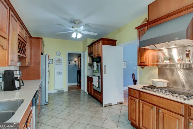a kitchen with stainless steel appliances granite countertop a refrigerator a stove and a sink with wooden cabinets