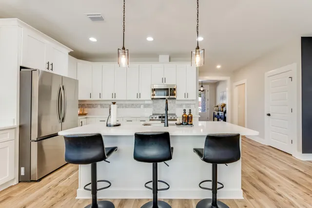 a kitchen with stainless steel appliances refrigerator dining table and chairs