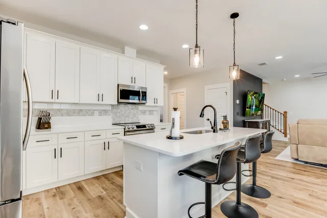 a kitchen with granite countertop a stove a sink a kitchen island with a dining table and chairs