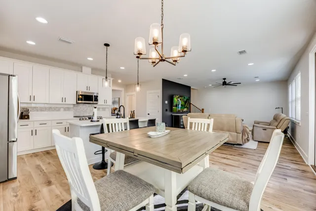 a view of a dining room and livingroom with furniture wooden floor a rug and a chandelier