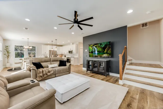 a living room with furniture and a flat screen tv with kitchen view