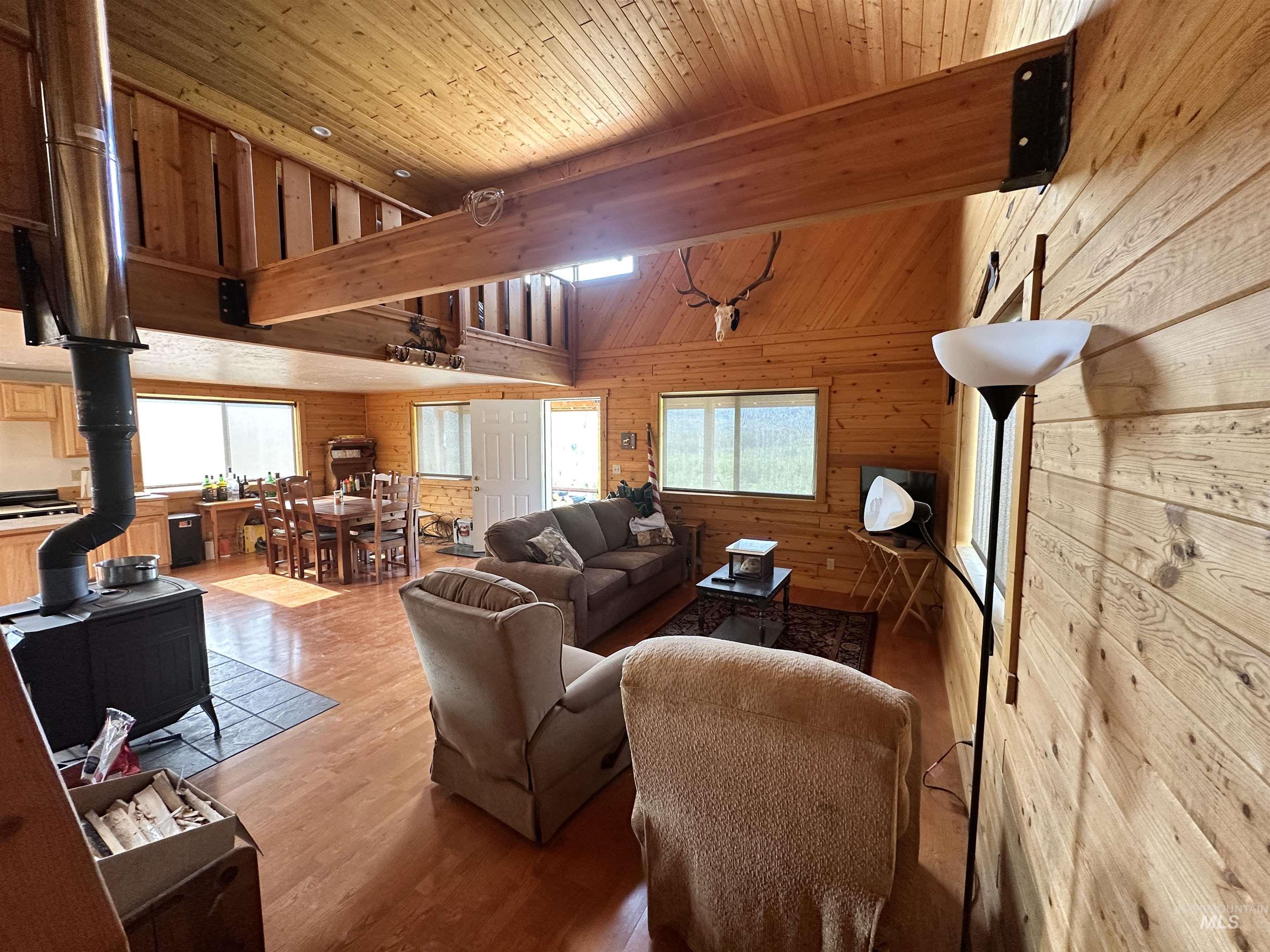532 Warren Creek Road McCall, ID 83638 - Photo 17 of 45 Living area with a wood stove, wood walls, healthy amount of natural light, light wood-style floors, and a wooden ceiling with exposed beams