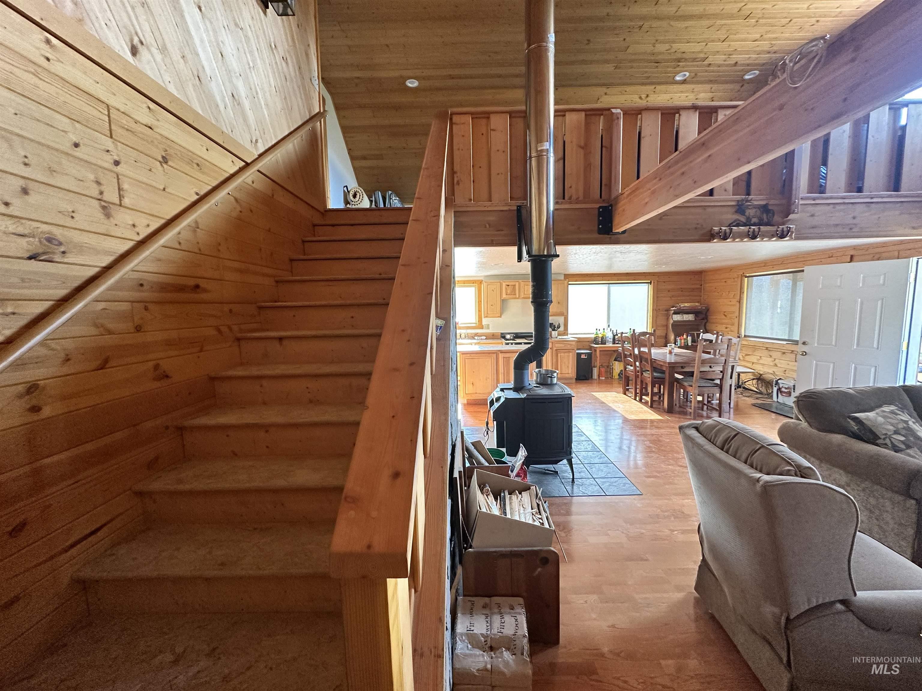 532 Warren Creek Road McCall, ID 83638 - Photo 18 of 45 Stairs featuring a wood stove, wood ceiling, wood finished floors, a towering ceiling, and wooden walls