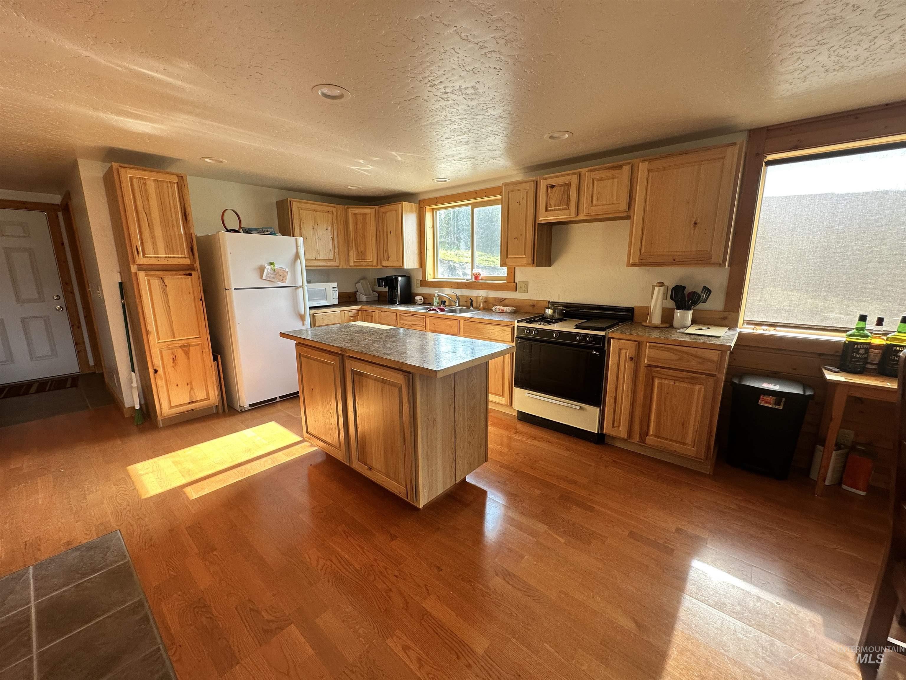 532 Warren Creek Road McCall, ID 83638 - Photo 7 of 45 Kitchen with white appliances, a textured ceiling, wood finished floors, a center island, and light countertops