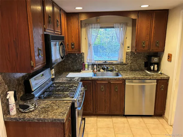 a kitchen with stainless steel appliances granite countertop a stove a sink and a microwave