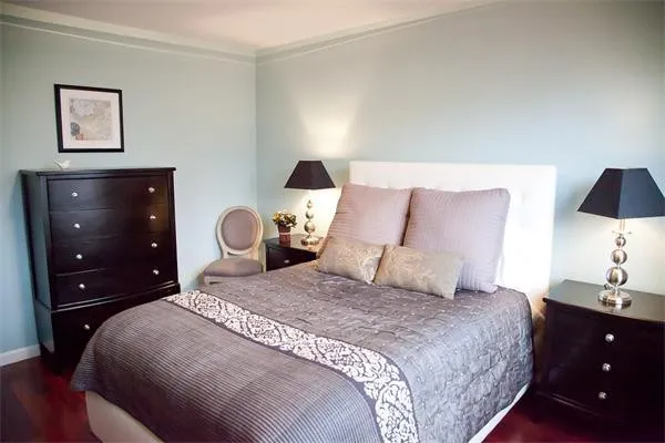 a bedroom with a bed and a lamp on dresser