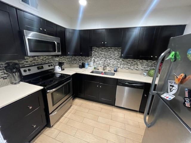 4245 Madera Road Irving, TX 75038 - Photo 4 of 10 Kitchen featuring dark cabinets, appliances with stainless steel finishes, and tasteful backsplash