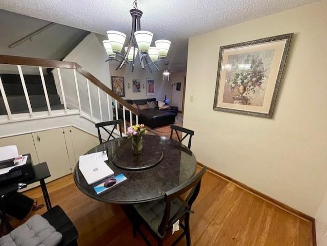 4245 Madera Road Irving, TX 75038 - Photo 5 of 10 Dining room with stairs, wood finished floors, a chandelier, and a textured ceiling