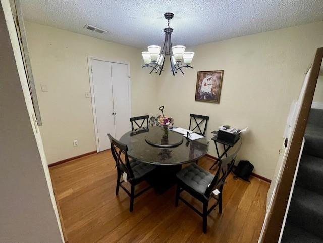 4245 Madera Road Irving, TX 75038 - Photo 6 of 10 Dining room featuring wood finished floors, a chandelier, and a textured ceiling