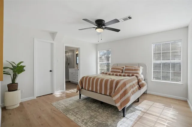 a bed sitting in a spacious bedroom next to a window and a chandelier