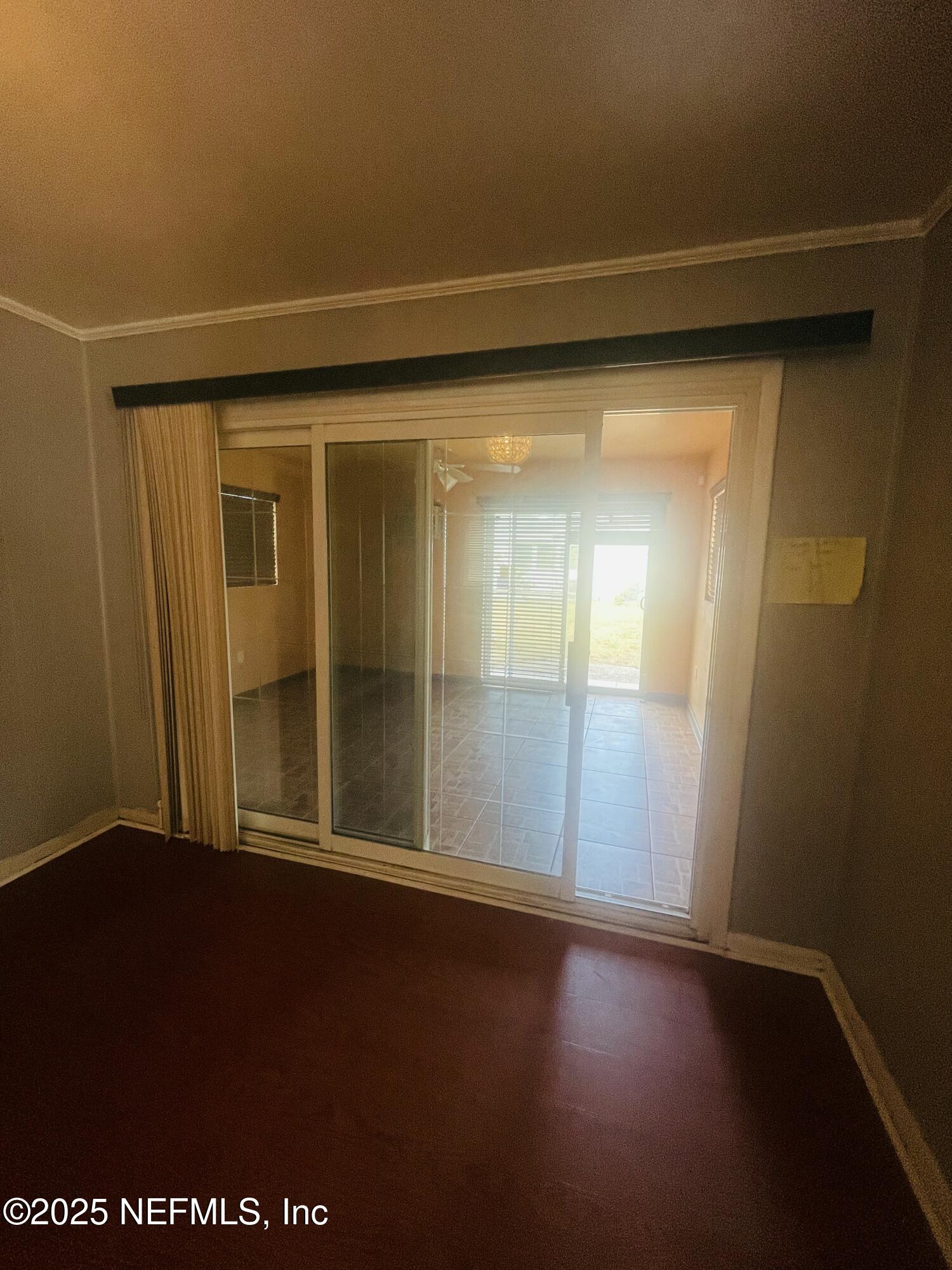 6643 Heidi Road Jacksonville, FL 32277 - Photo 13 of 45 an empty room with wooden floor and windows with curtains