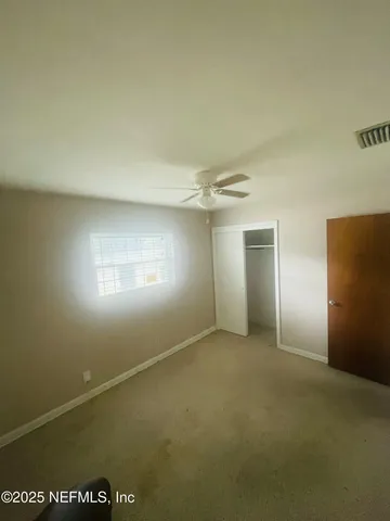 an empty room with a window and a fan