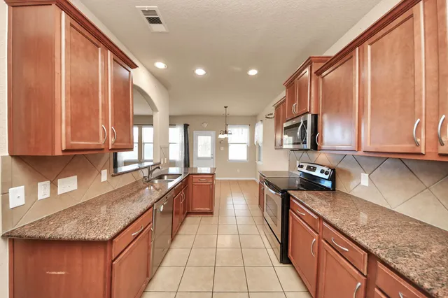 a large kitchen with stainless steel appliances granite countertop a sink stove and cabinets