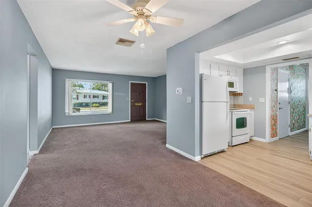 an empty room with windows and ceiling fan