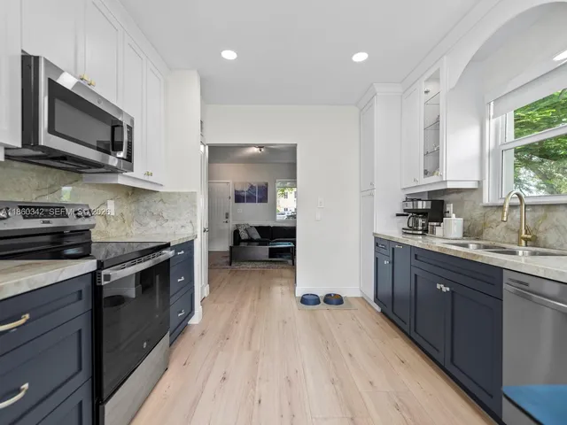 a kitchen with stainless steel appliances a stove top oven a sink dishwasher and a microwave oven with wooden floor