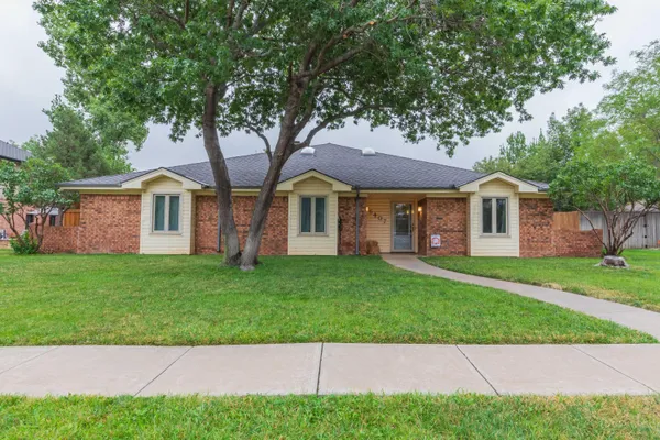 a front view of a house with a garden and trees