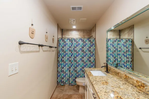 a bathroom with a granite countertop sink a toilet and shower