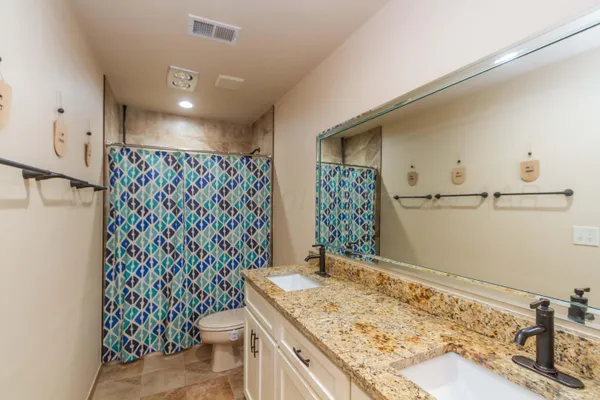 a bathroom with a granite countertop sink and a toilet