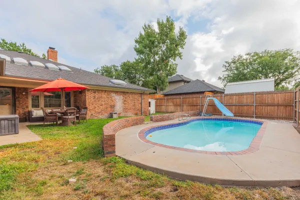 a view of pool with umbrella and table