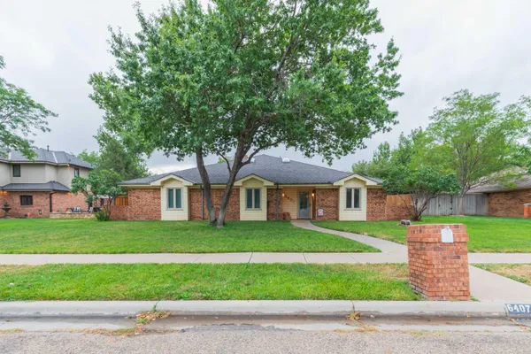 a front view of a house with a yard and trees