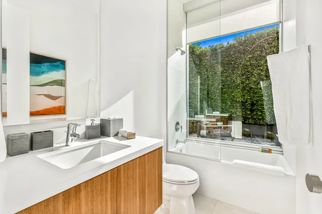 a bathroom with a granite countertop sink toilet and a large mirror
