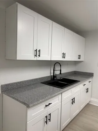 a kitchen with granite countertop white cabinets and a sink