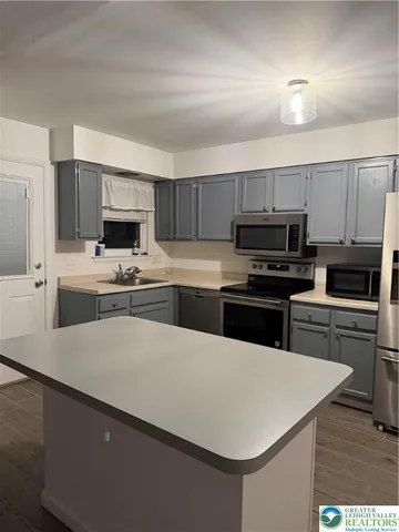 a kitchen with kitchen island a sink stove and microwave