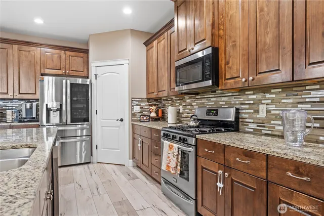 a kitchen with stainless steel appliances granite countertop a refrigerator stove top oven and sink