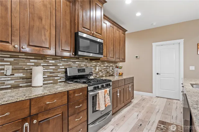 a kitchen with stainless steel appliances granite countertop a stove a sink and a microwave