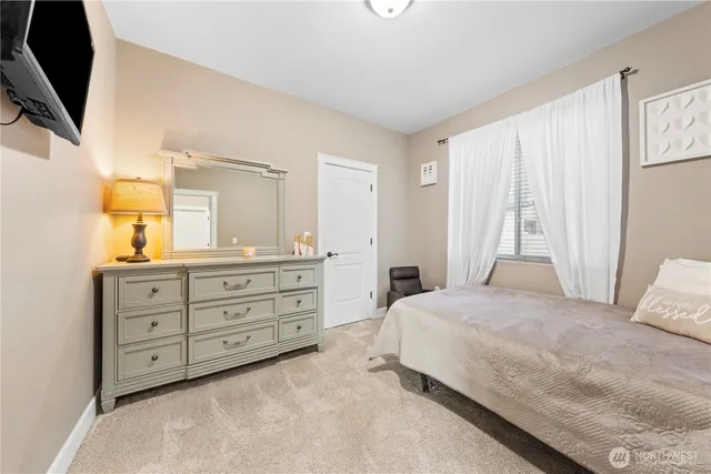 a bedroom with a large bed and a flat tv screen on dresser