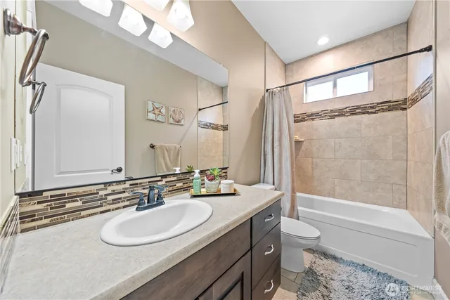 a bathroom with a sink a toilet a mirror a bathtub and shower