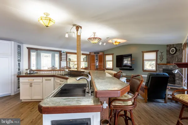 a kitchen with a stove a sink dishwasher a dining table and chairs with wooden floor