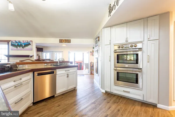 a kitchen with stainless steel appliances white cabinets and wooden floor