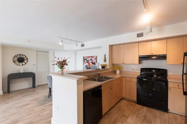 a kitchen with stainless steel appliances a sink dishwasher stove refrigerator and cabinets