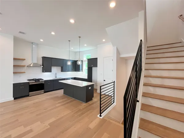 a large kitchen with stainless steel appliances kitchen island granite countertop a stove a sink and a refrigerator